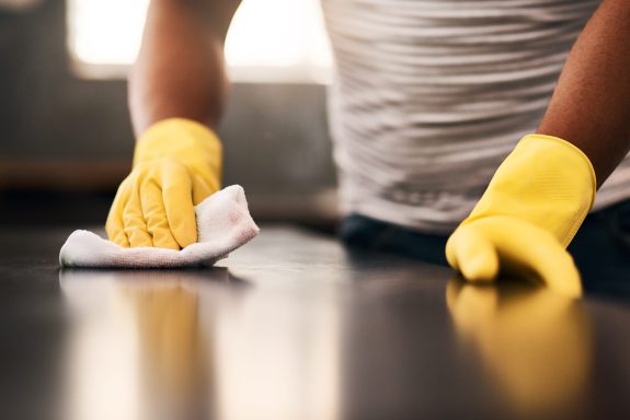 Cropped shot of an unrecognizable man cleaning a kitchen counter at home.
