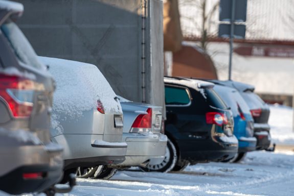row of different cars parked  in the outdoor parking lot on a snowy winter day