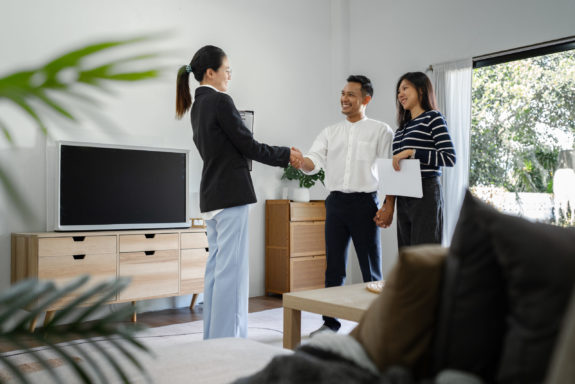 Young happy smiling couple read agreement with realtor and looking through the contract of real estate sale going to signing a deal.